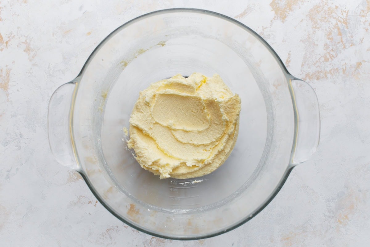 Butter and sugar creamed together in a glass mixing bowl until light and fluffy.