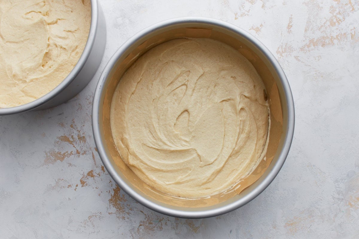 Two round cake pans filled with smooth yellow cake batter, ready to be baked.