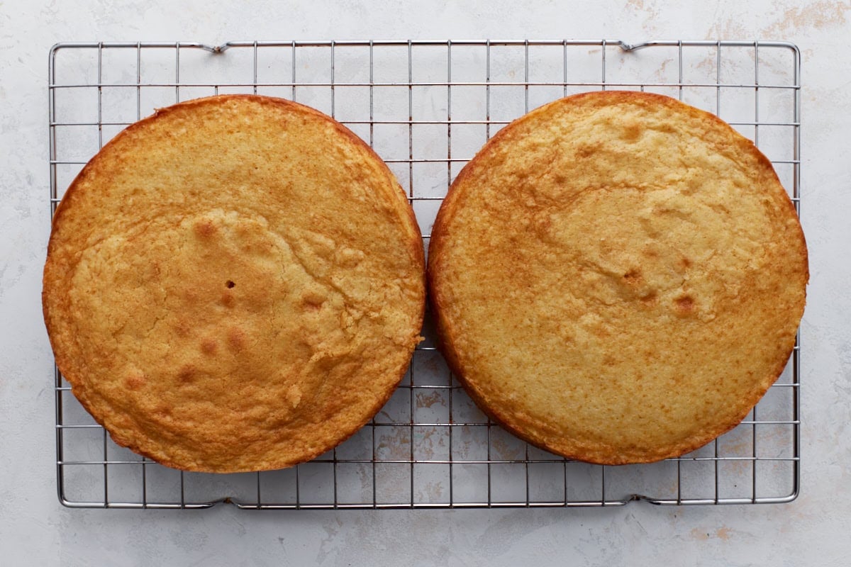 Two golden gluten-free yellow cake layers cooling on a wire rack.