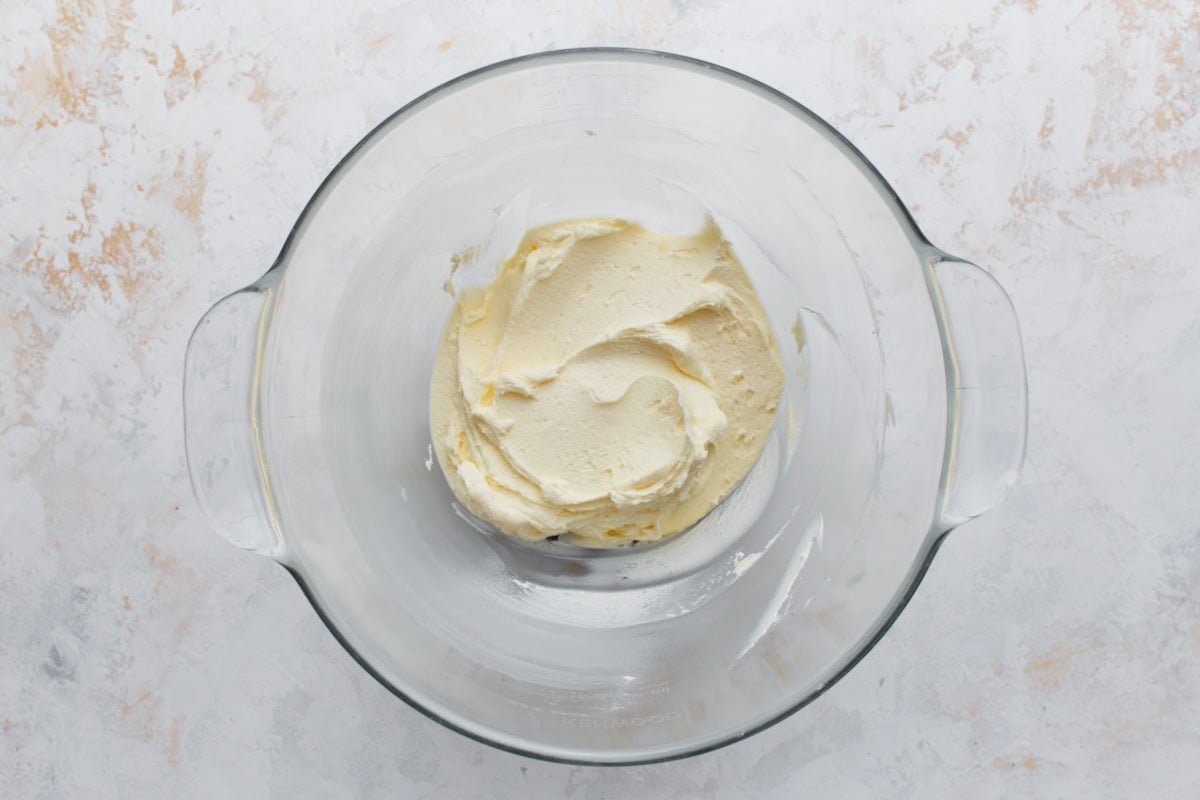 Softened butter whipped until creamy in a glass mixing bowl, ready for frosting preparation.