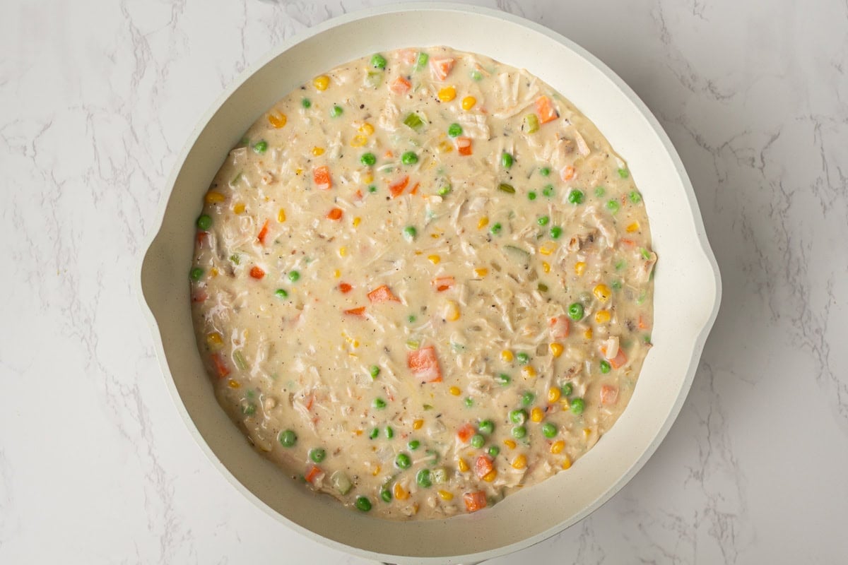 Thickened chicken pot pie filling with peas, carrots, corn, and chicken ready to serve.
