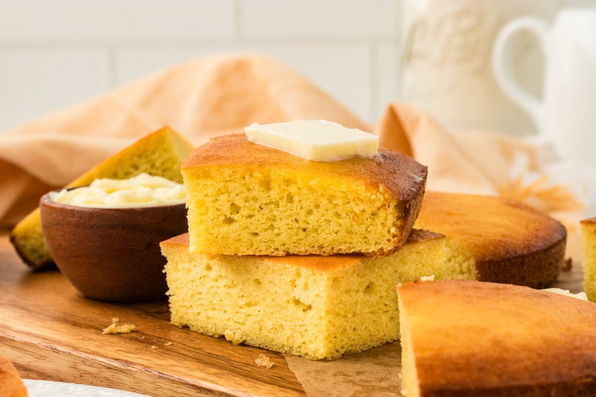 Stack of keto cornbread slices with a pat of butter melting on top, showing the light, fluffy crumb.