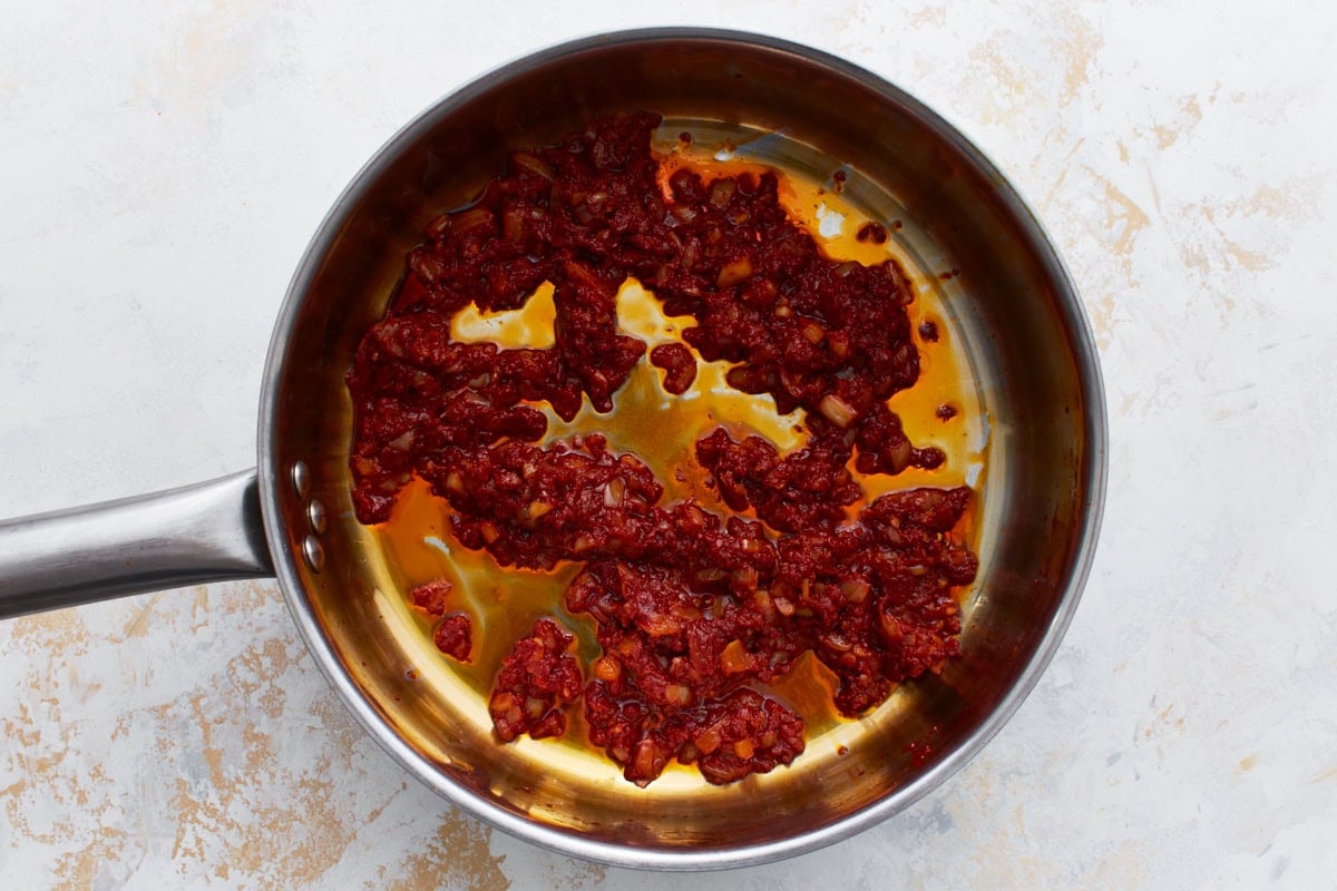 Tomato paste added to the skillet with onions and garlic, starting to cook down.
