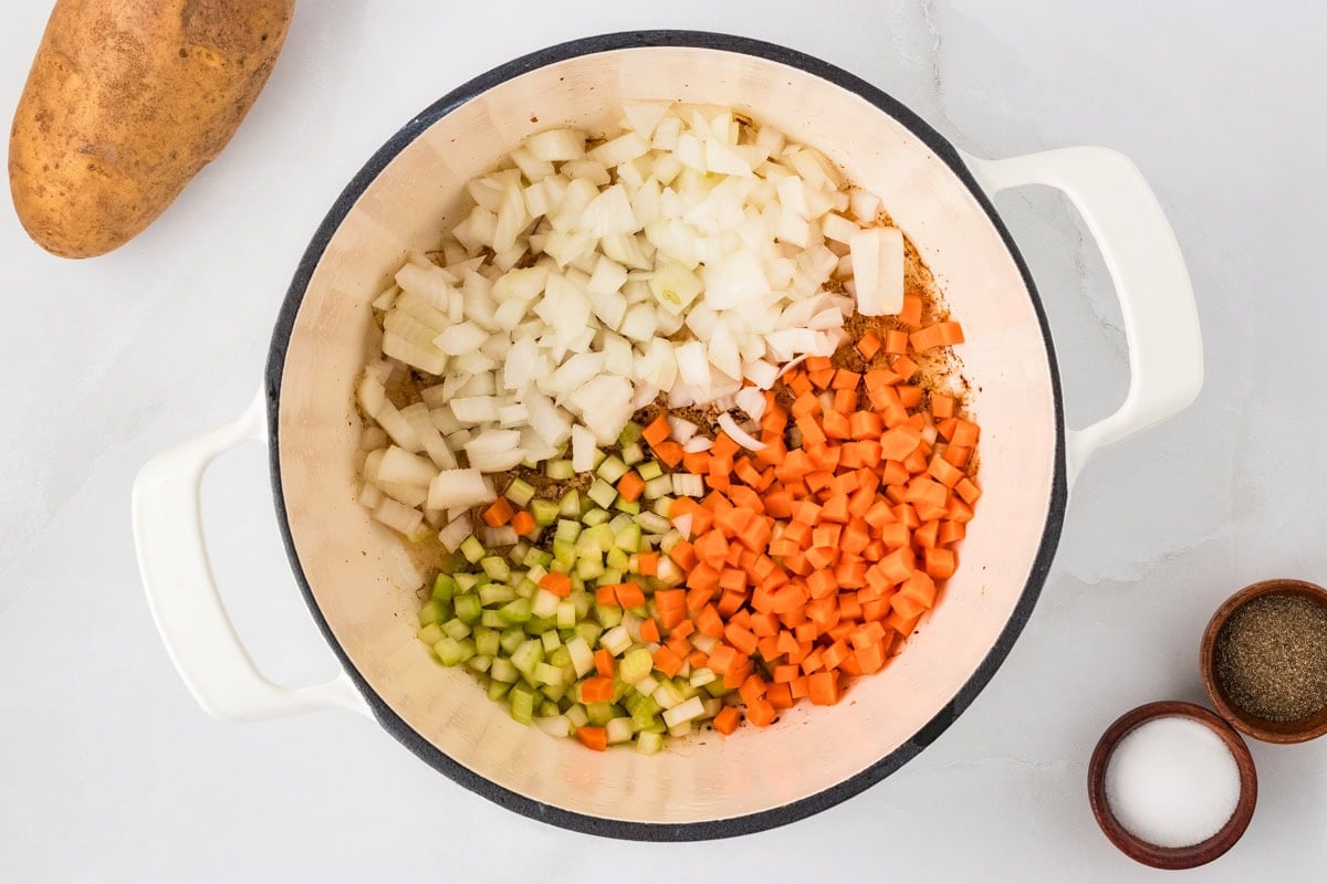 Diced onion, carrot, and celery added to the pot with bacon drippings, ready to sauté for the soup base.