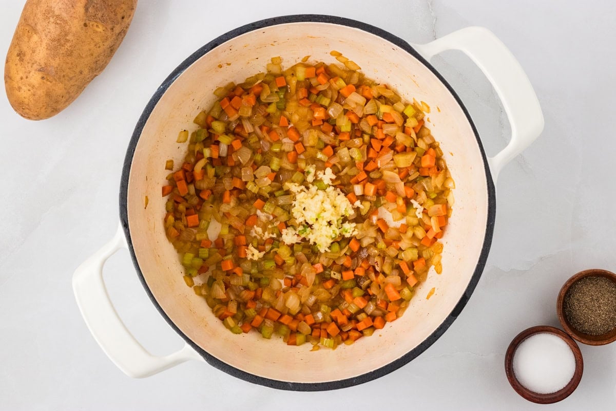 Sautéed onion, carrot, and celery softened in the pot with freshly minced garlic added to the center.