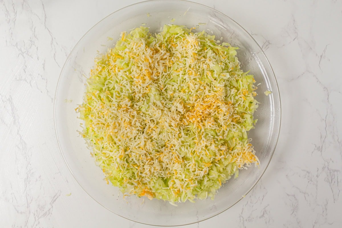 Shredded zucchini layered with grated Colby Jack and Gruyere cheese in a pie plate.