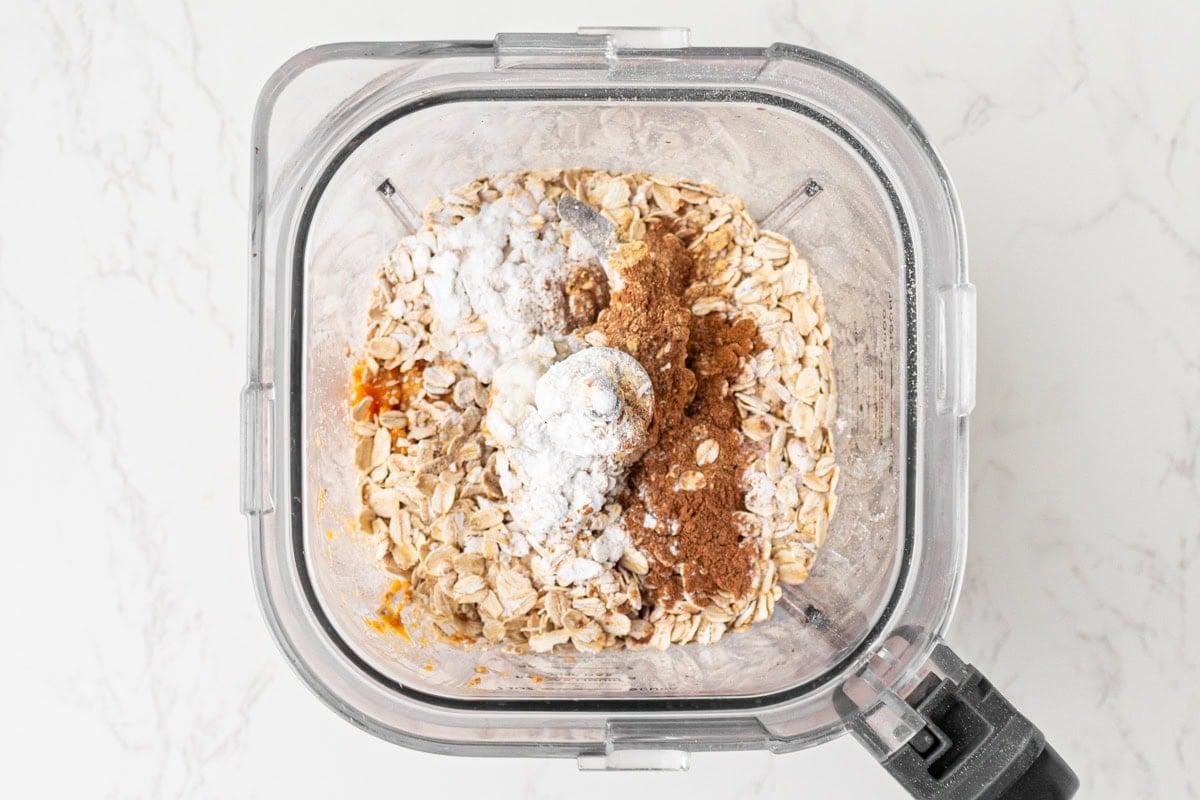 Rolled oats, baking powder, cinnamon, pumpkin spice, and ginger added to the wet pumpkin mixture in the blender.