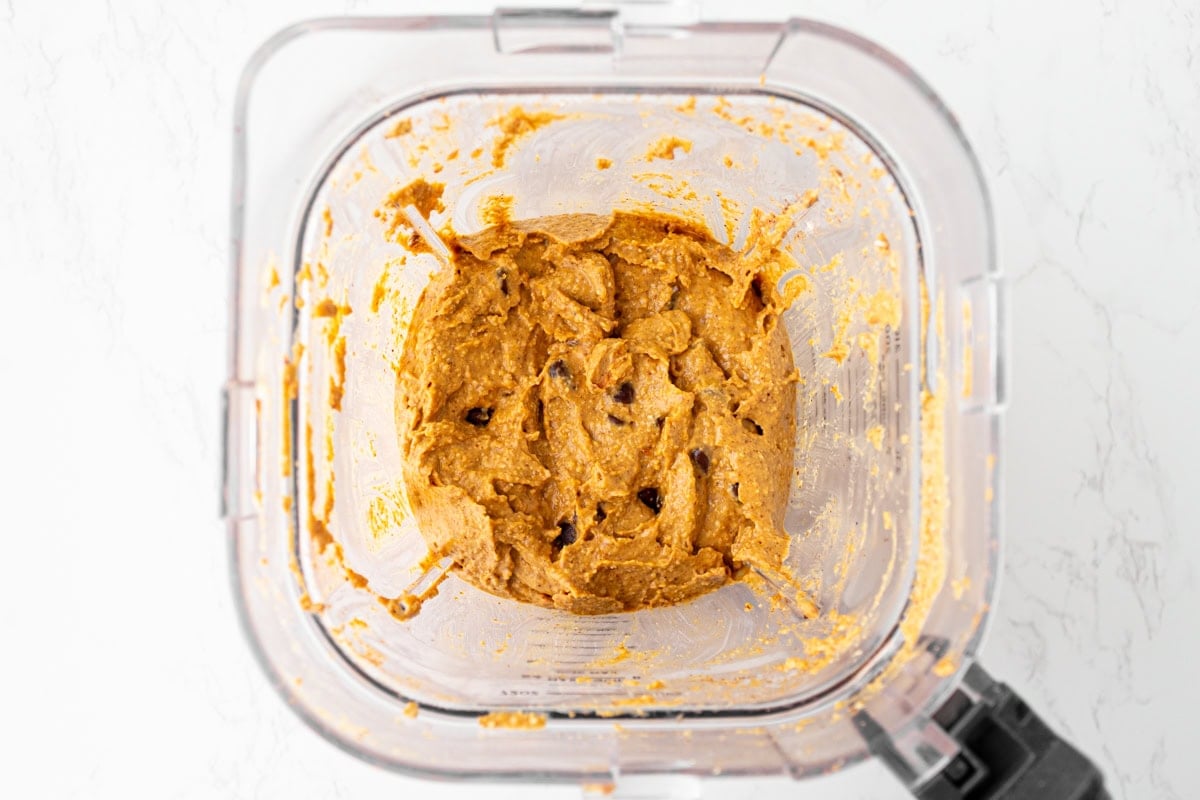 Pumpkin muffin batter fully blended with chocolate chips stirred in, thick and creamy in the blender bowl.