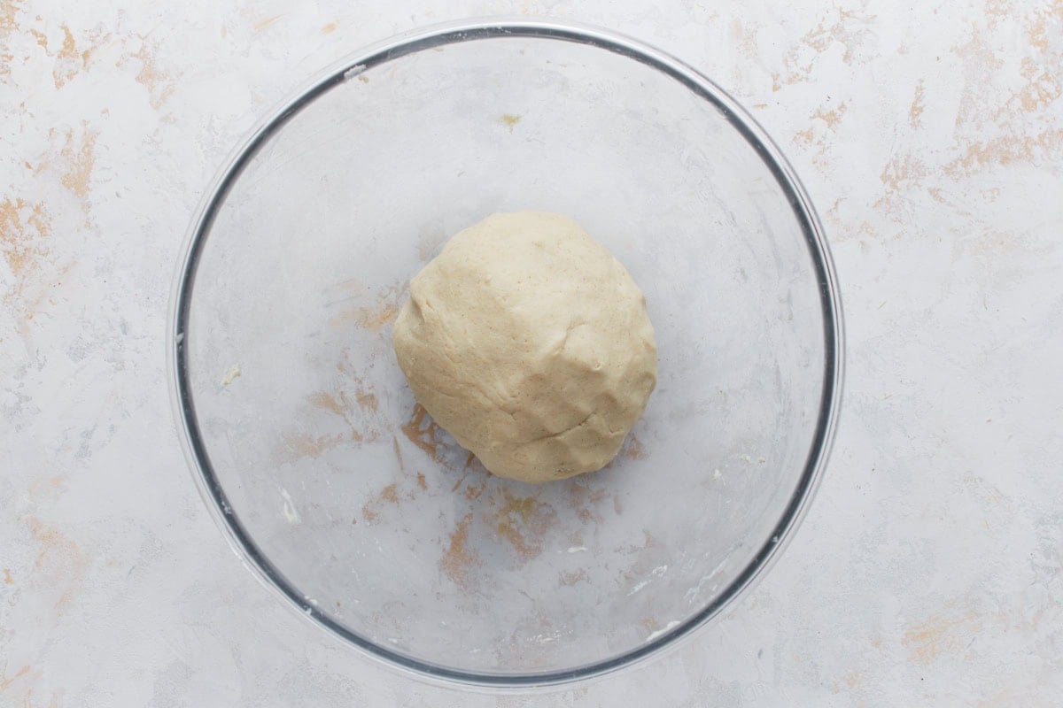 Ball of gluten-free masa dough in a glass mixing bowl on a light surface.
