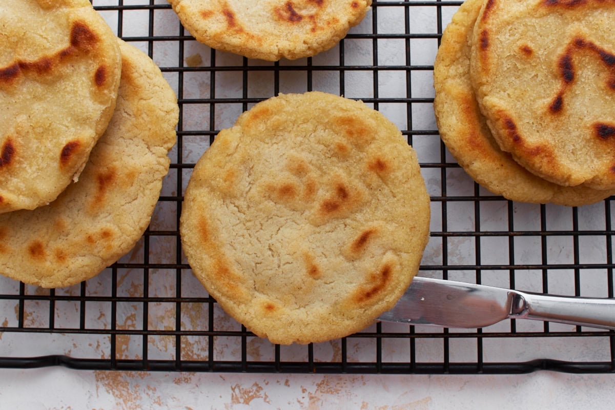 Cooked gorditas cooling on a wire rack, showing their lightly golden and fluffy texture.