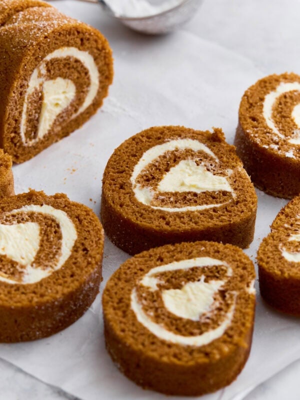 Close-up of gluten-free pumpkin roll sliced into swirls with cream cheese filling, dusted lightly with powdered sugar.