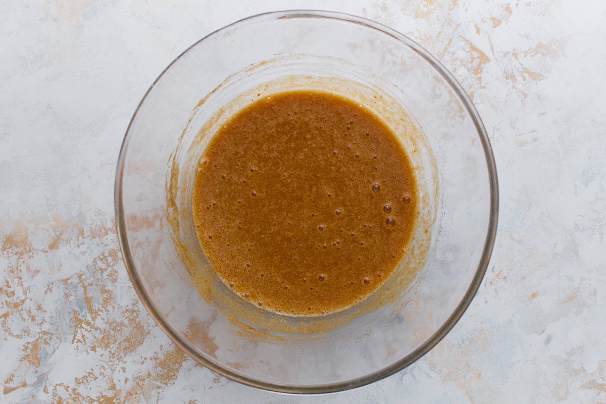 Pumpkin puree and spices mixed into the egg and sugar base, creating a light orange-brown batter.