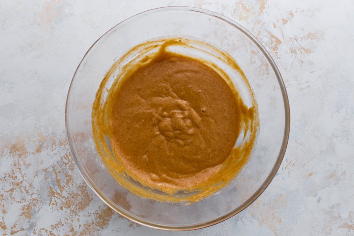 Gluten-free flour folded into the pumpkin mixture, forming a smooth, thicker cake batter.