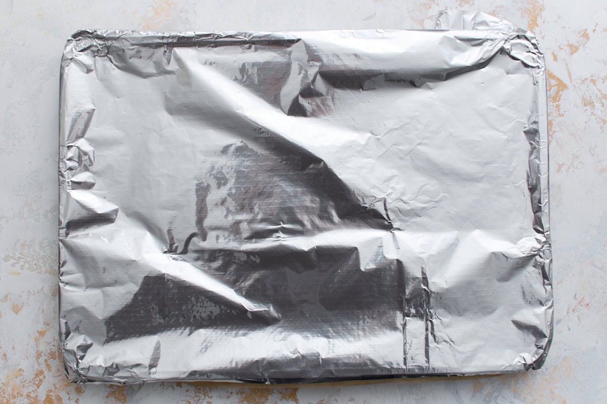 Jelly roll pan covered with aluminum foil, allowing the pumpkin cake to cool to room temperature.