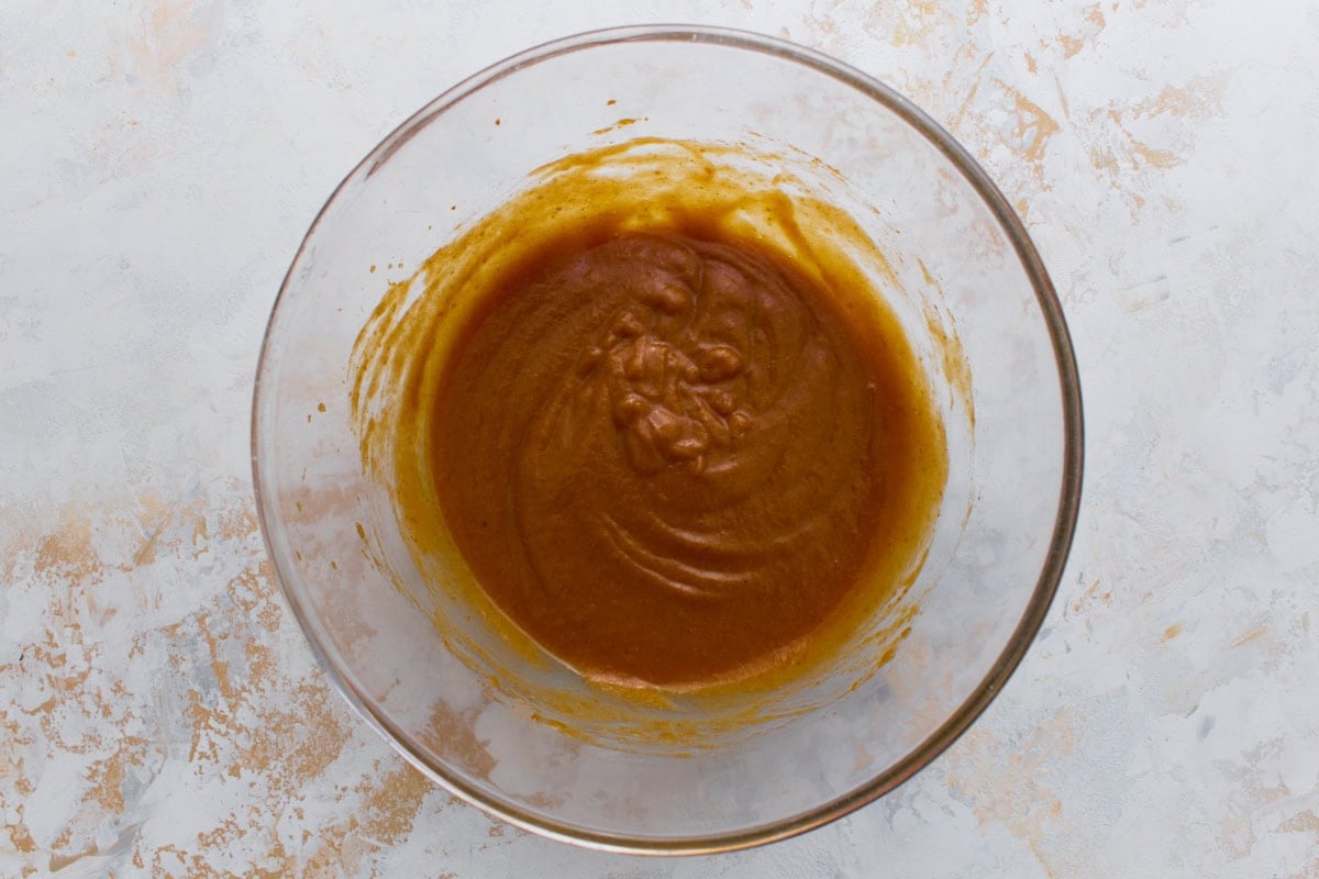 Pumpkin waffle batter in a glass bowl after adding wet ingredients.