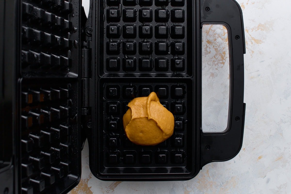 Scoop of pumpkin waffle batter placed in the center of a hot waffle iron.
