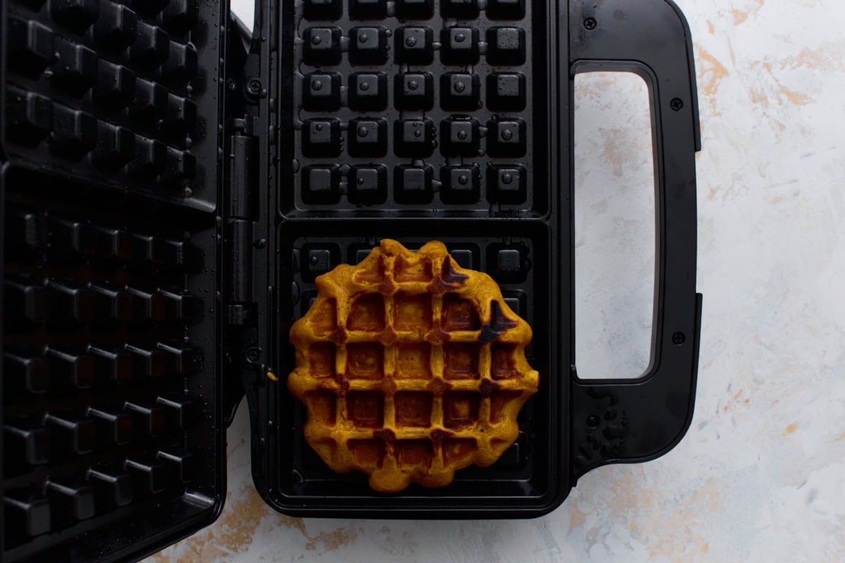 Freshly cooked pumpkin waffle inside a waffle iron.