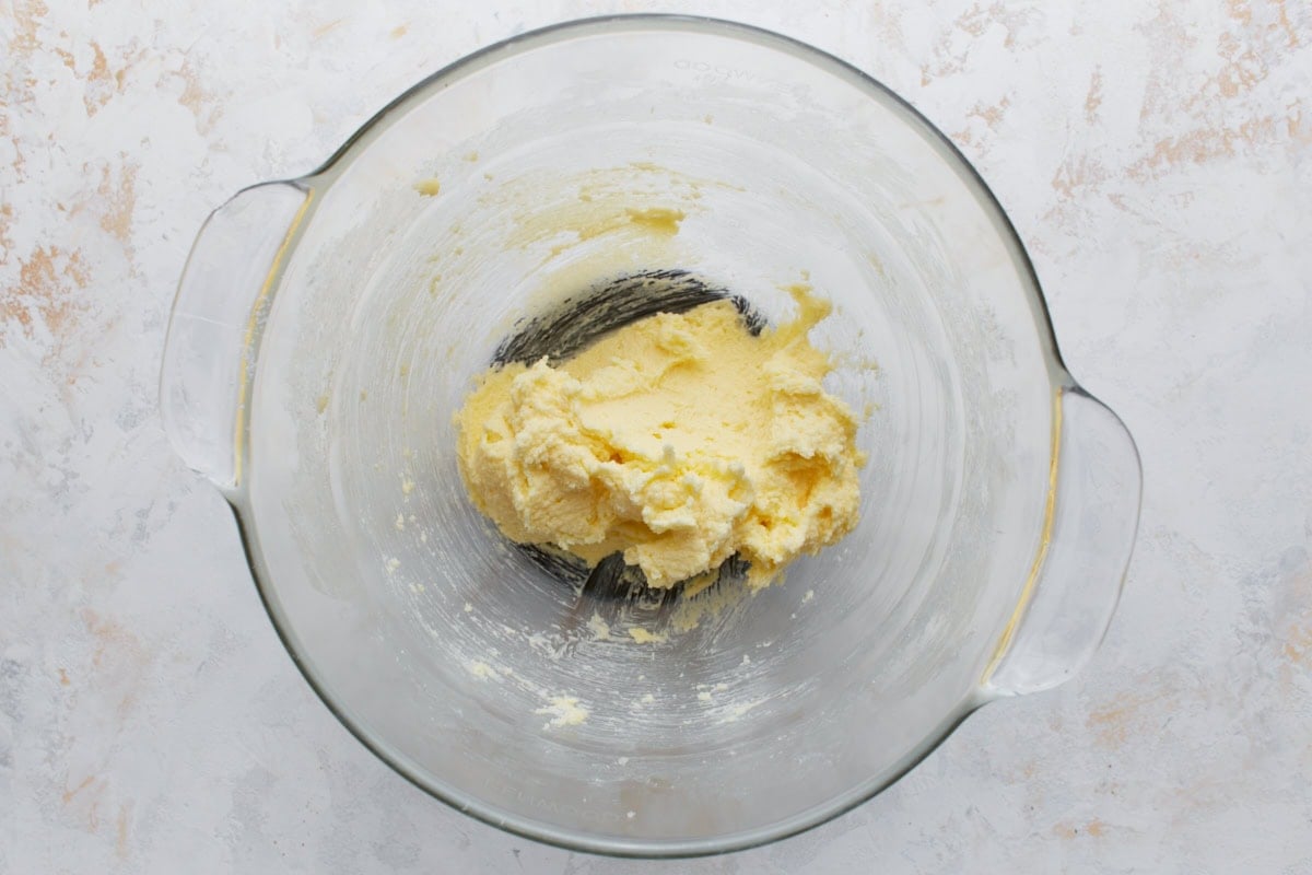 A glass bowl filled with creamed butter and sugar that’s light and fluffy, the first step in making snickerdoodle cookie dough.