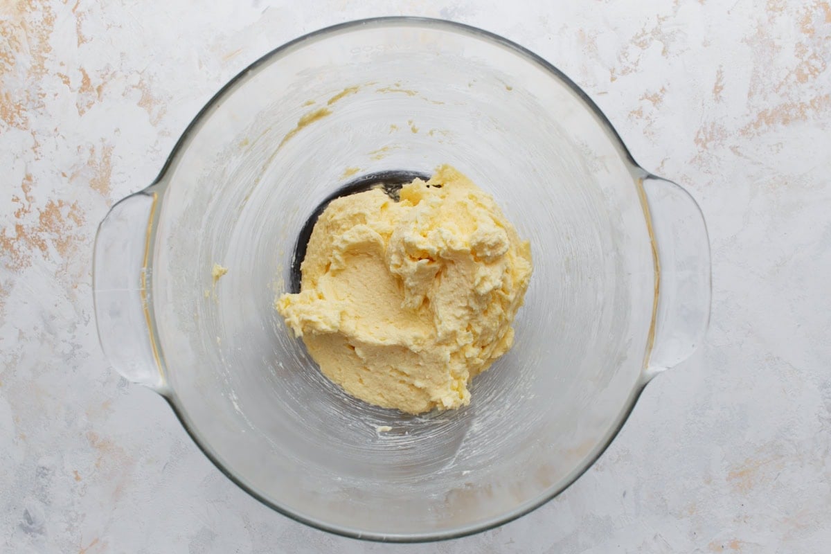 Light, thick butter mixture in a glass bowl, evenly whipped and ready for the gluten-free flour blend.