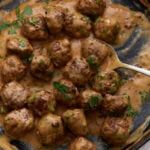 Keto Swedish meatballs in a creamy sauce garnished with fresh parsley in a skillet.