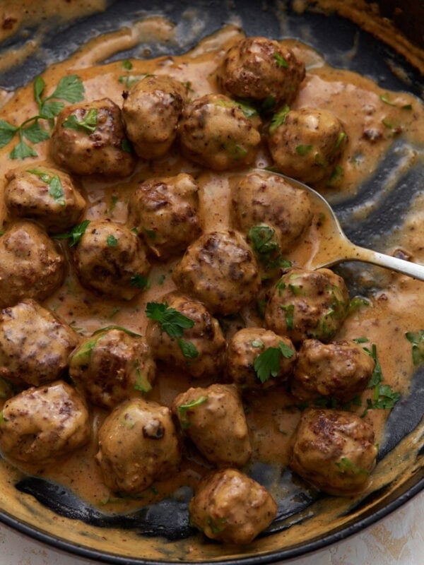 Keto Swedish meatballs in a creamy sauce garnished with fresh parsley in a skillet.