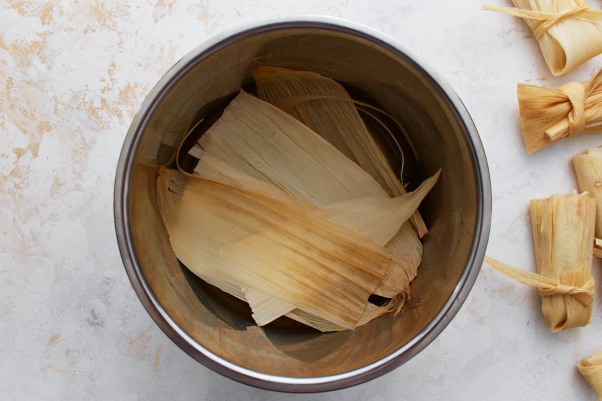 A few soaked corn husks placed at the bottom of a metal pot to line the steamer.