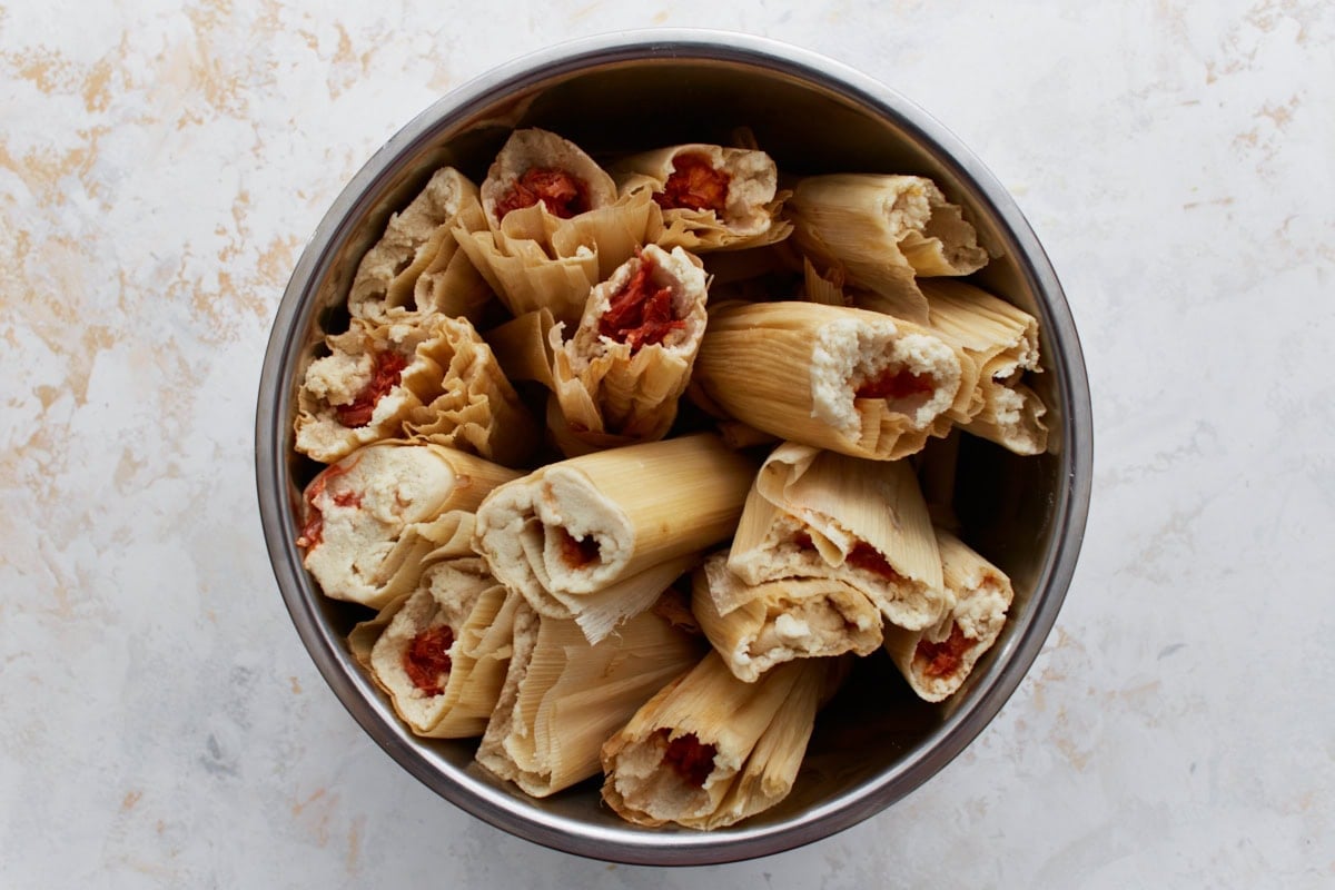 Filled tamales arranged upright in a pot with open ends facing up, ready to be steamed.