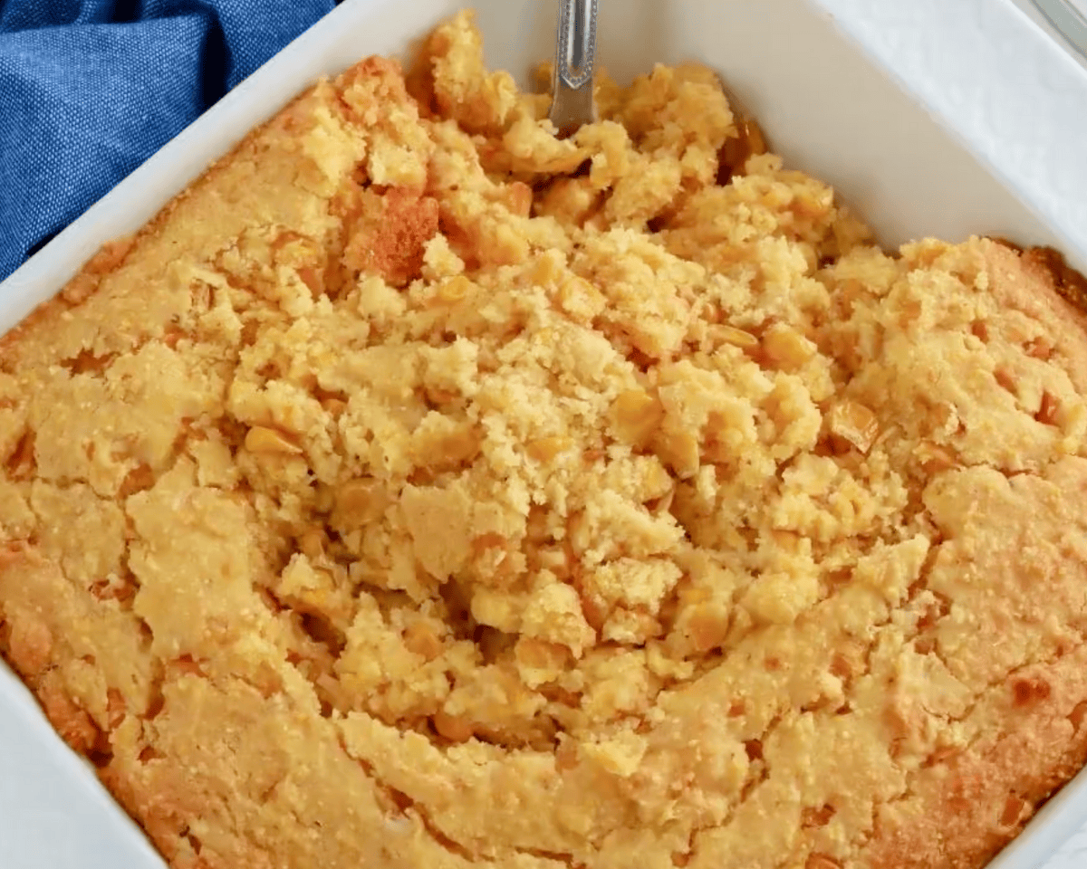 Close-up of soft, custardy gluten-free corn casserole being scooped from the baking dish, showing the tender, fluffy texture.