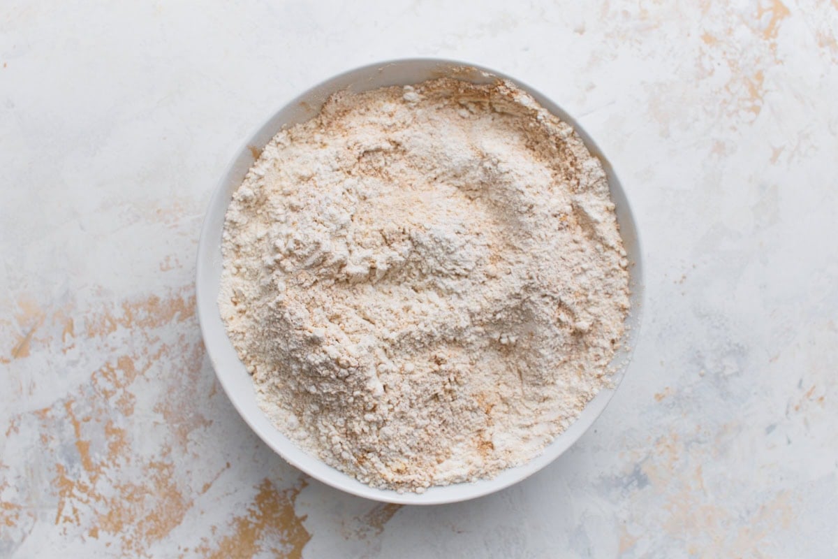 A bowl of gluten-free flour mixed with ginger, cinnamon, cloves, baking soda, and salt.