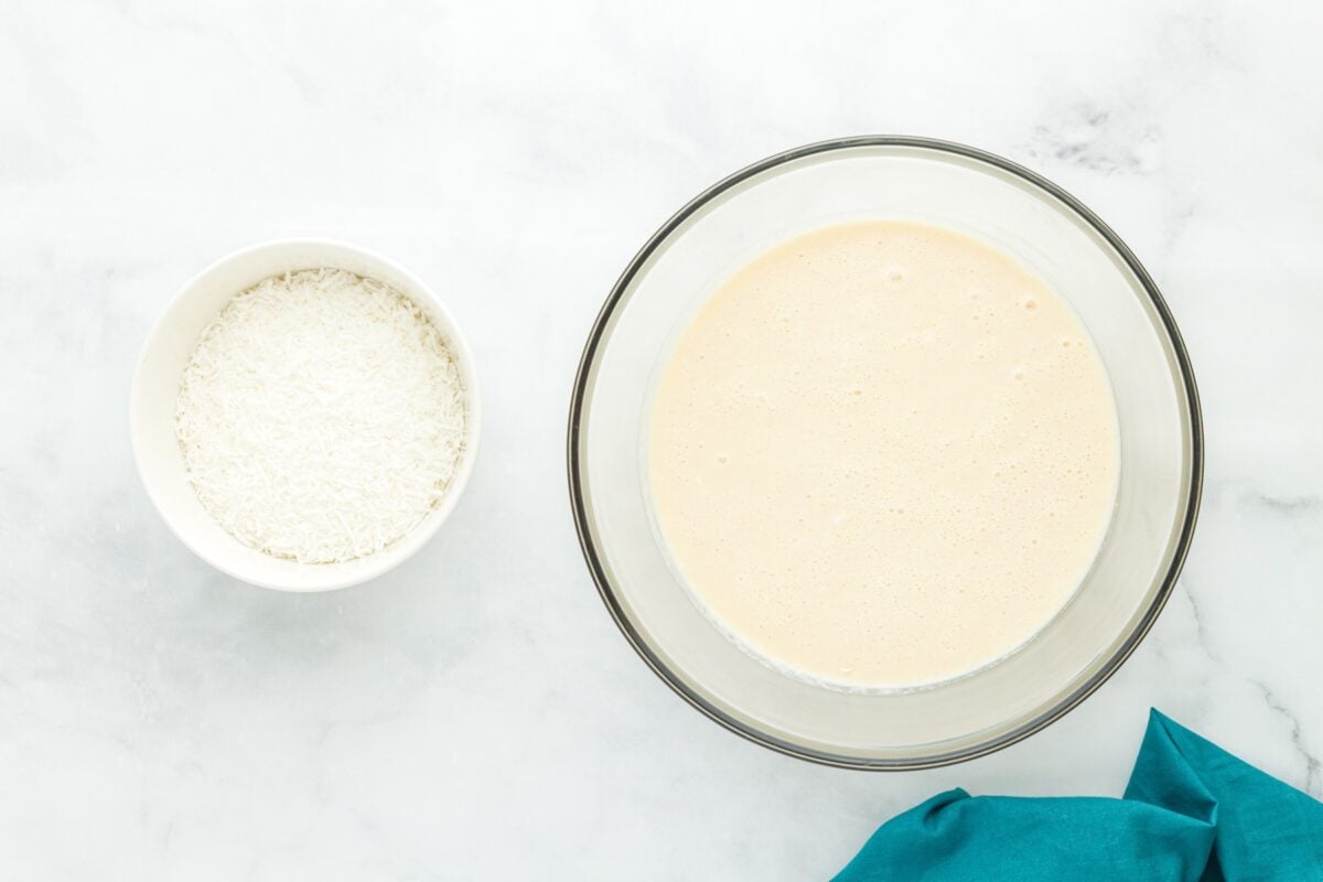 Bowl of shredded sweetened coconut beside a bowl of smooth pie batter.