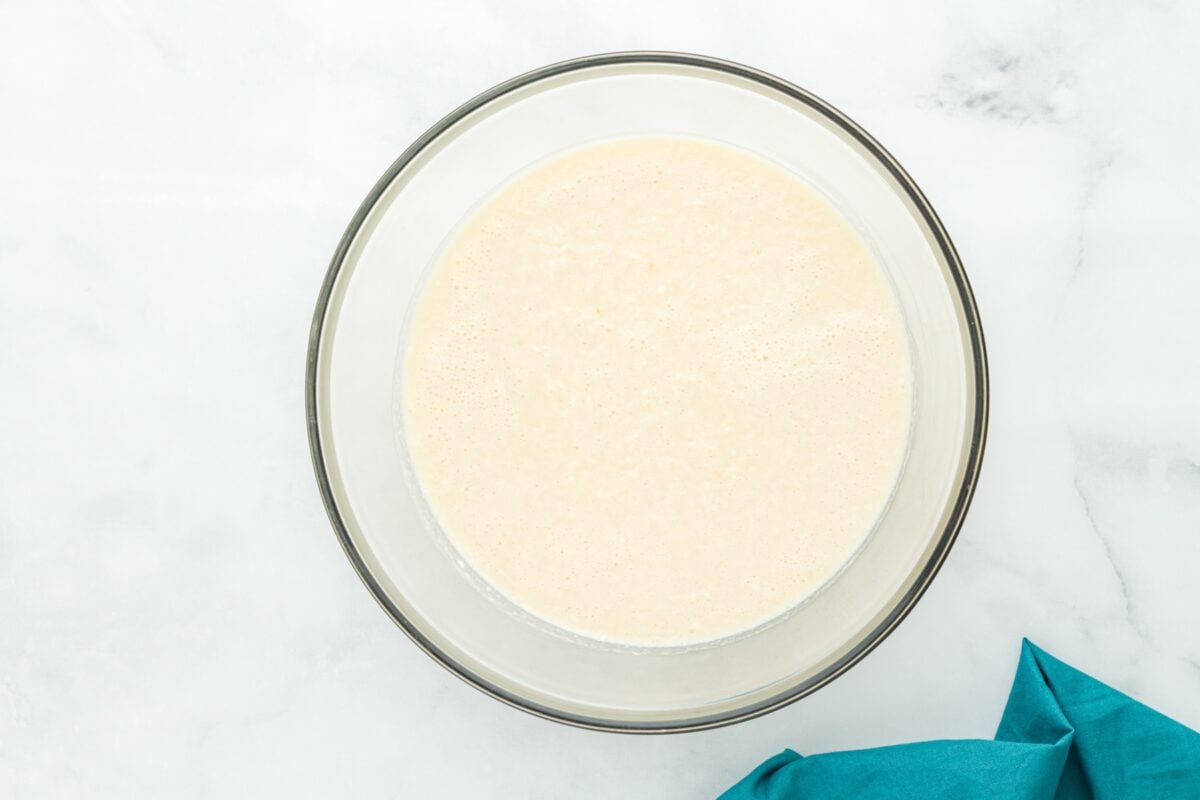 Pie batter mixed with shredded coconut in a glass bowl ready to pour.