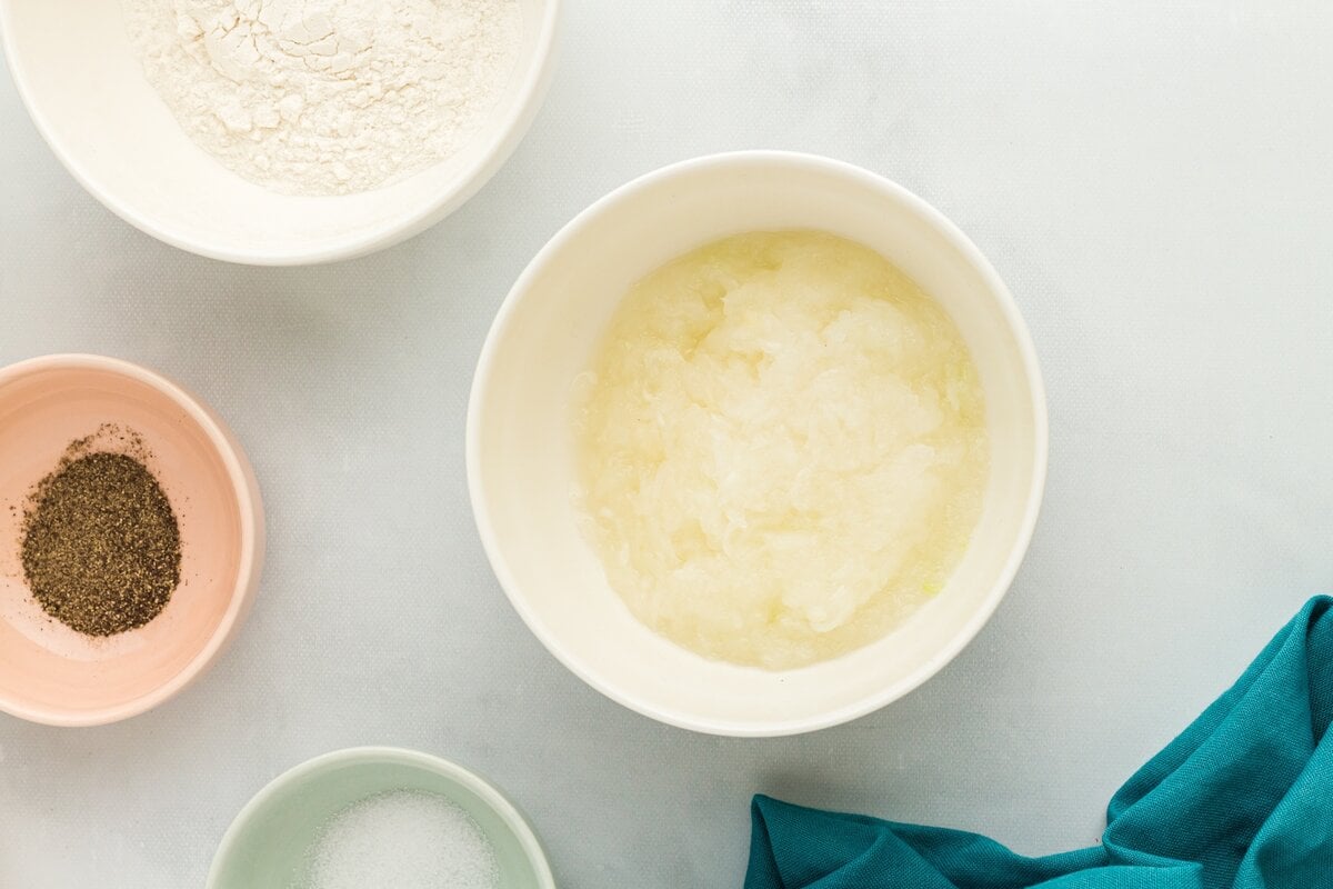 Finely grated onion in a small bowl, ready to be mixed into the potato latke batter.