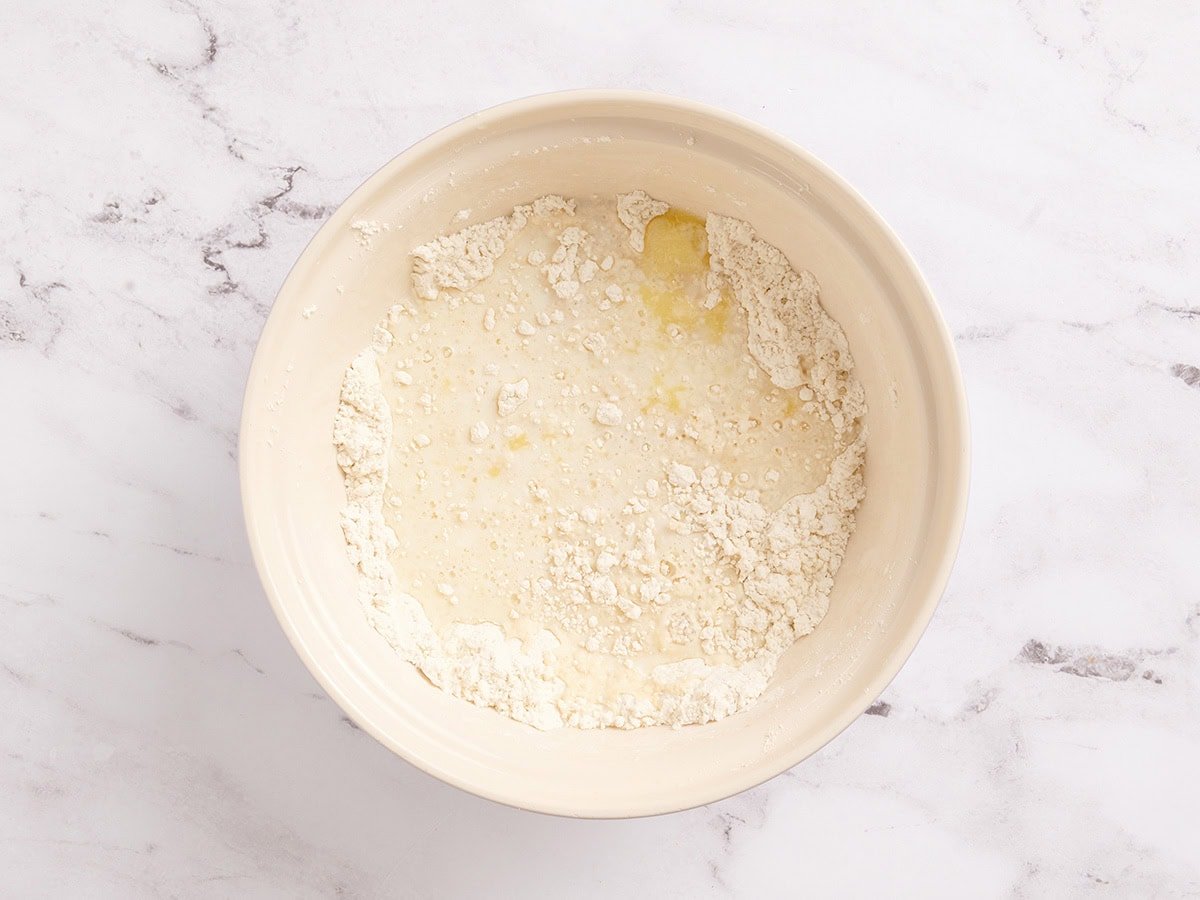 Warm milk, warm water, and melted butter added to the bowl of dry gluten free dough ingredients.