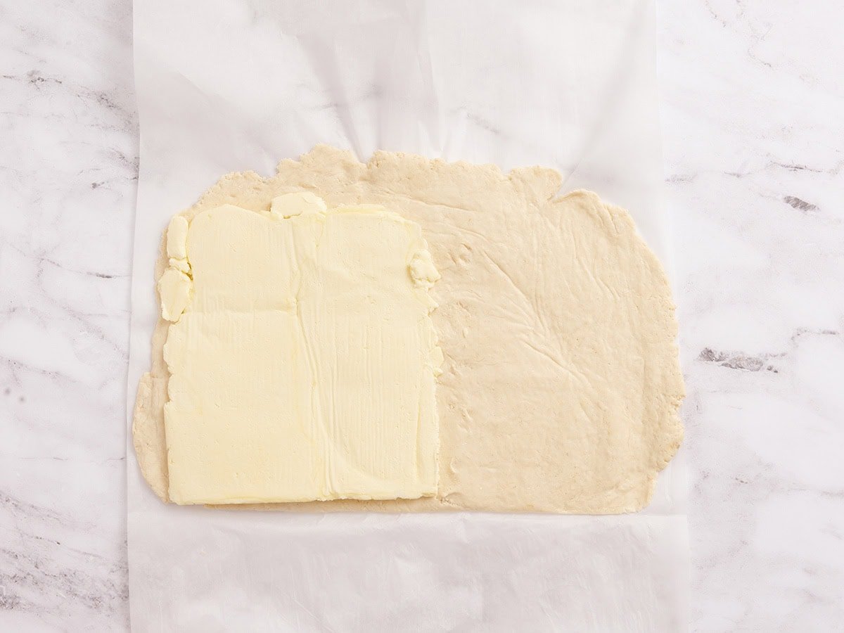 Chilled butter block placed on one half of the rolled-out gluten free dough.