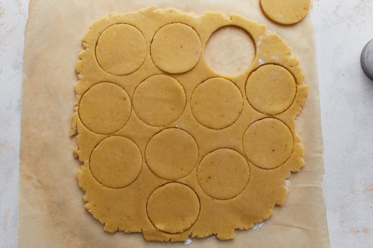 Rolled-out almond flour sugar cookie dough with round cookie shapes cut out.