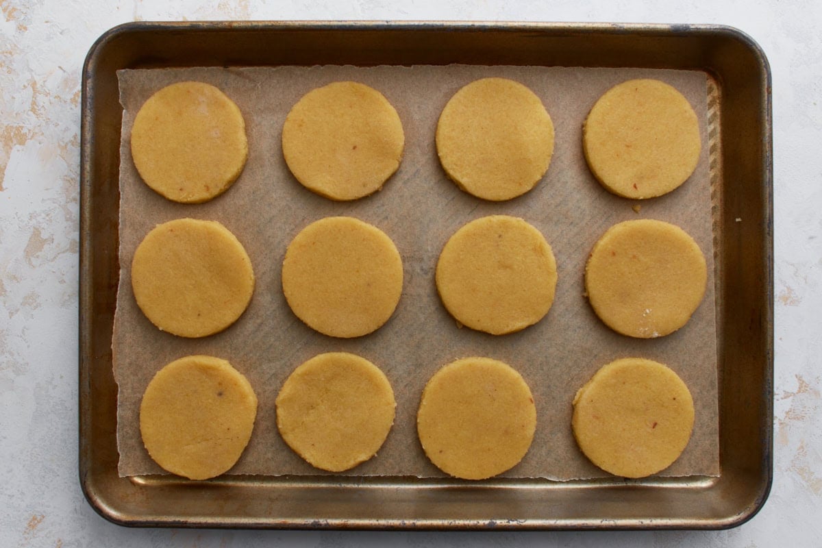 Unbaked almond flour sugar cookies arranged evenly on a parchment-lined baking sheet.