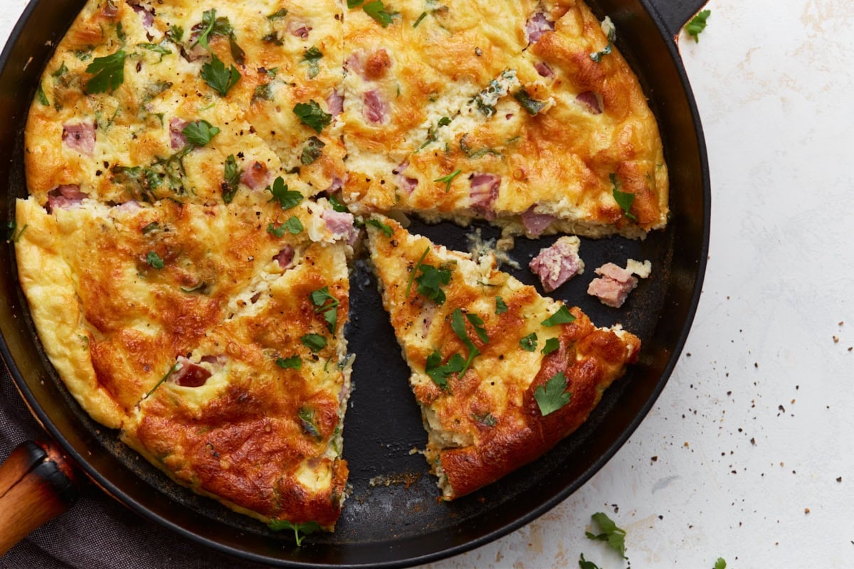 Crustless ham and cheese quiche sliced into wedges in a skillet.