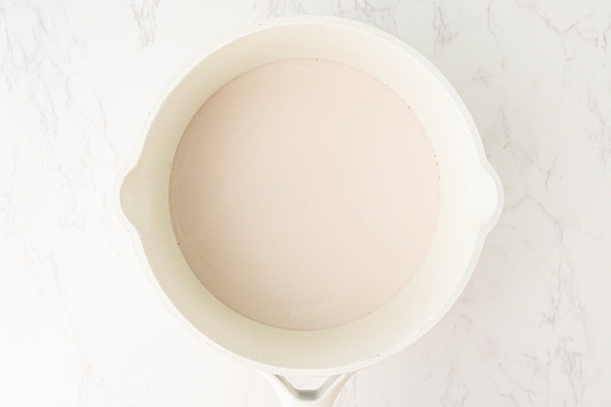 Warm coconut milk mixture resting in a saucepan after heating.