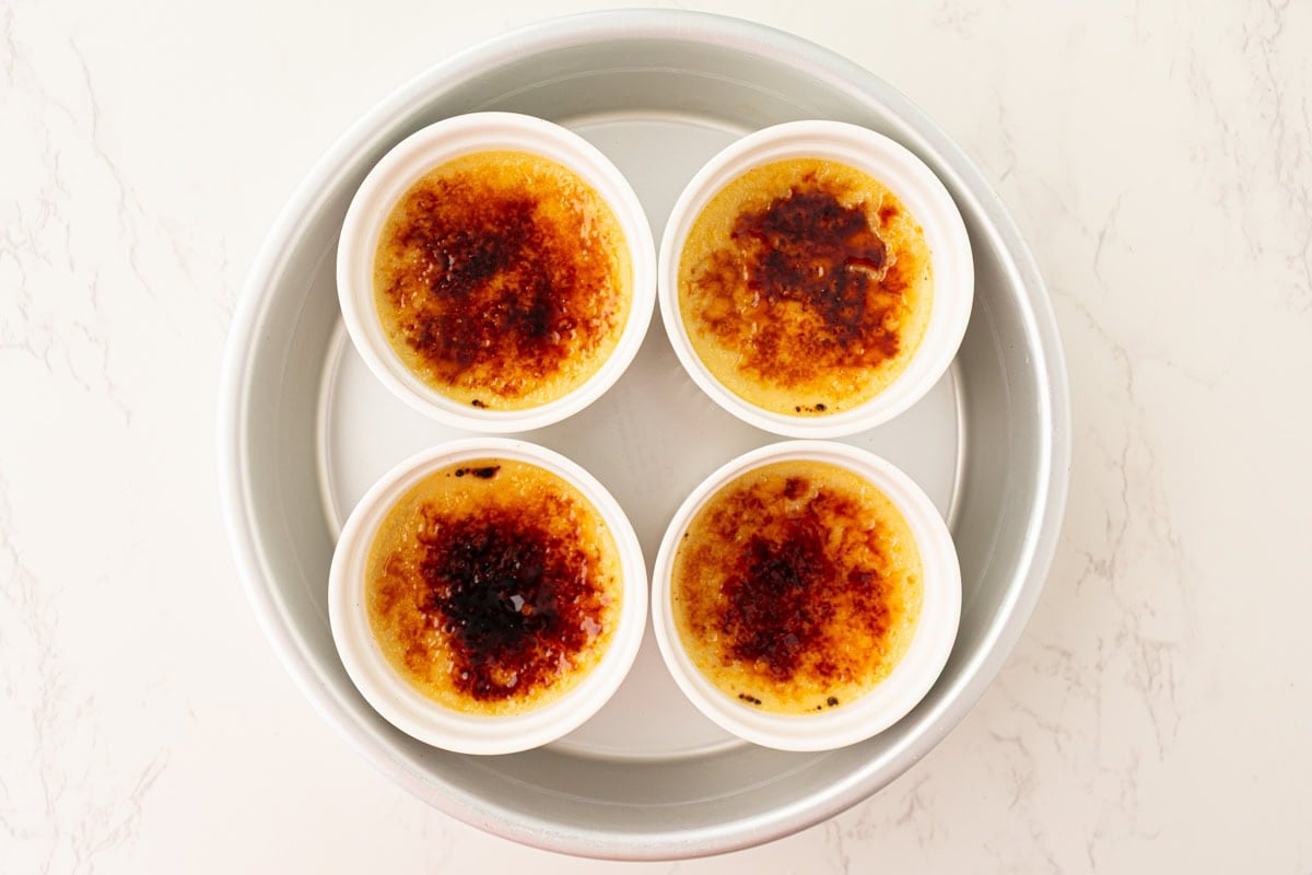 Four dairy-free crème brûlée custards with caramelized sugar tops sitting in a round baking dish.