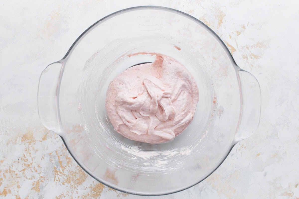 Light pink macaron batter after folding, showing thick ribbon consistency.