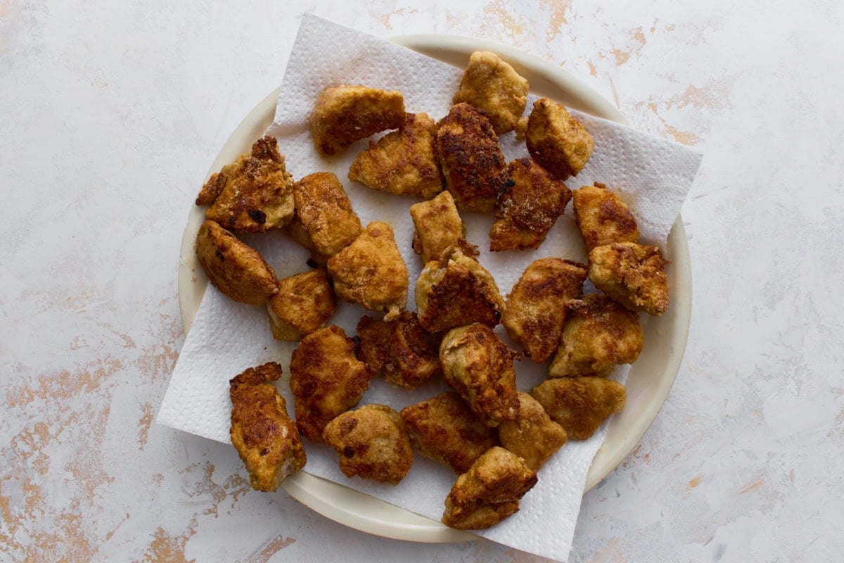 Crispy gluten-free fried chicken pieces resting on paper towels after shallow frying