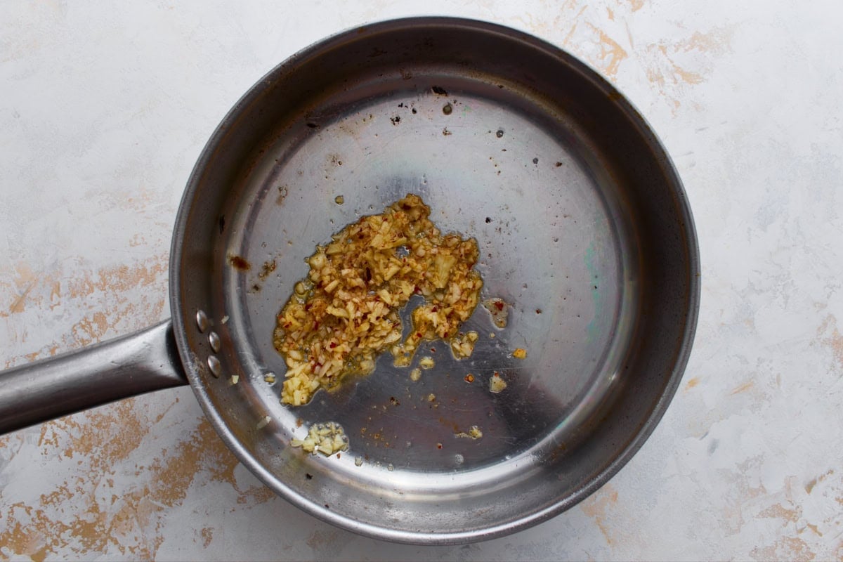 Minced garlic, ginger, and red pepper flakes sautéing in sesame oil in a skillet