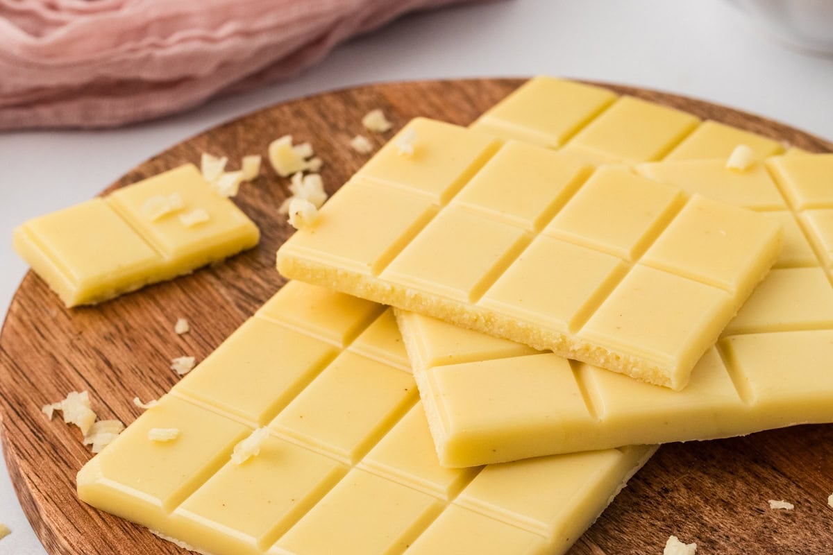 Close-up of vegan white chocolate bars on a wooden board showing smooth surface and texture.