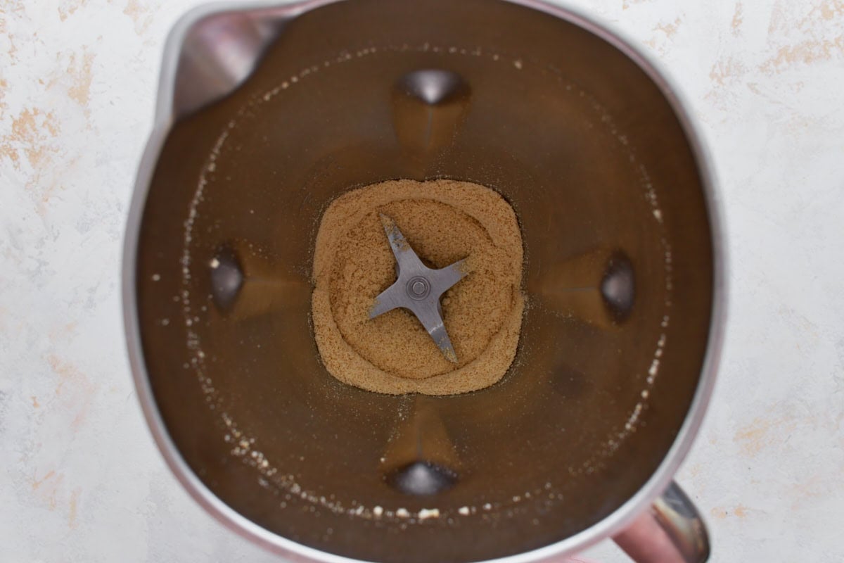 Vegan parmesan cheese blended to a fine, crumbly texture inside a blender.