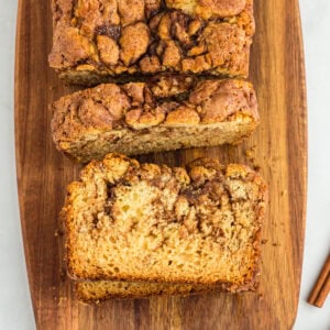 Gluten-free cinnamon bread sliced on a wooden cutting board, showing a soft crumb and cinnamon swirl.