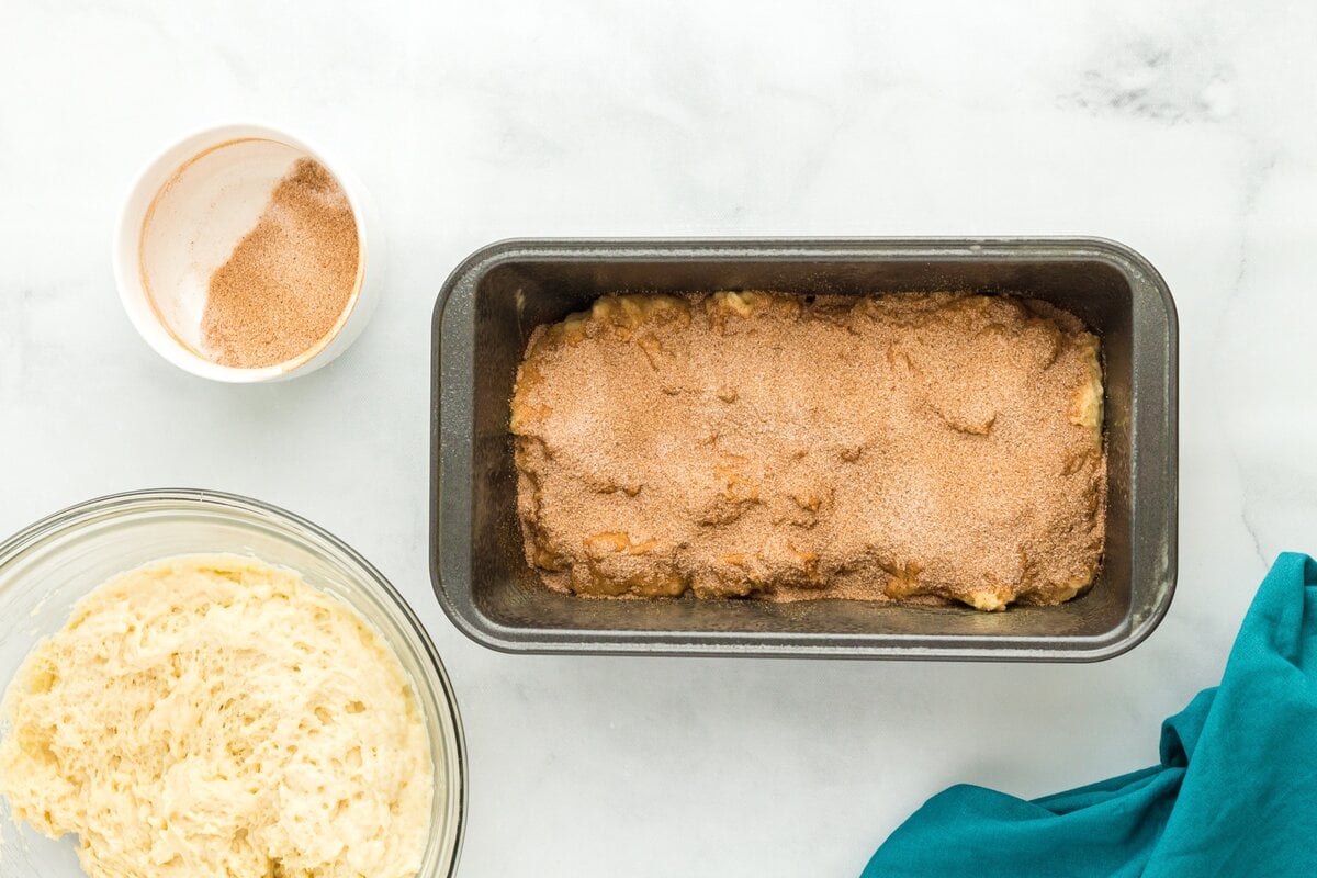 Gluten-free cinnamon bread batter spread in a loaf pan and topped with cinnamon sugar.