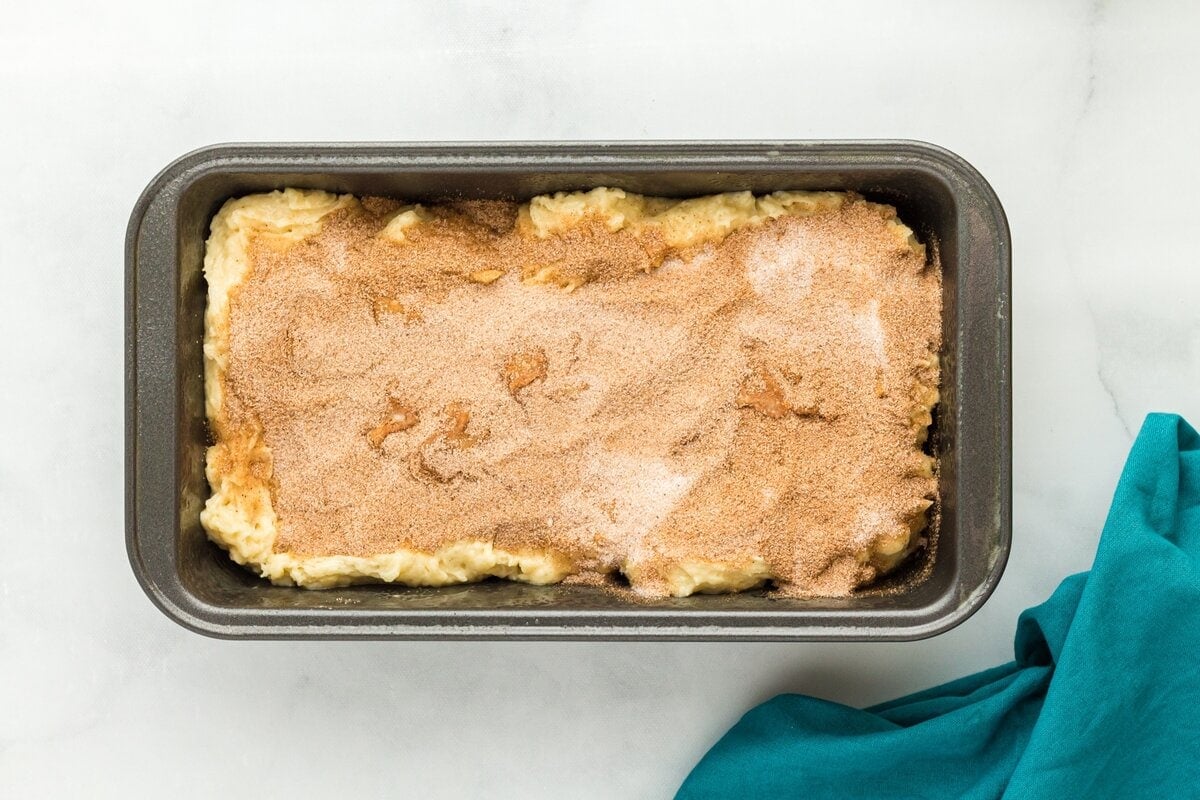 Cinnamon sugar sprinkled evenly over the top of gluten-free cinnamon bread batter.