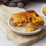 Slice of gluten-free breakfast casserole with sausage, hash browns, eggs, and melted cheese served on a small plate.