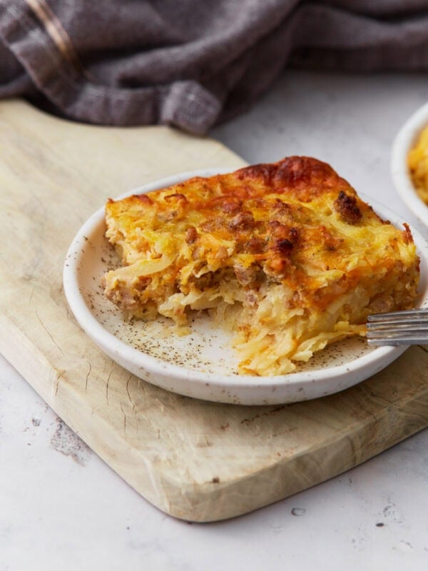 Slice of gluten-free breakfast casserole with sausage, hash browns, eggs, and melted cheese served on a small plate.