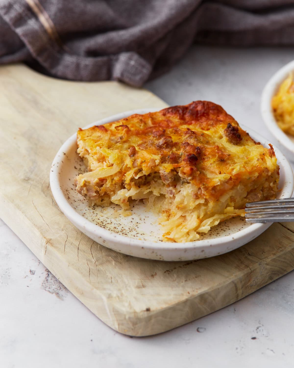 Slice of gluten-free breakfast casserole with sausage, hash browns, eggs, and melted cheese served on a small plate.